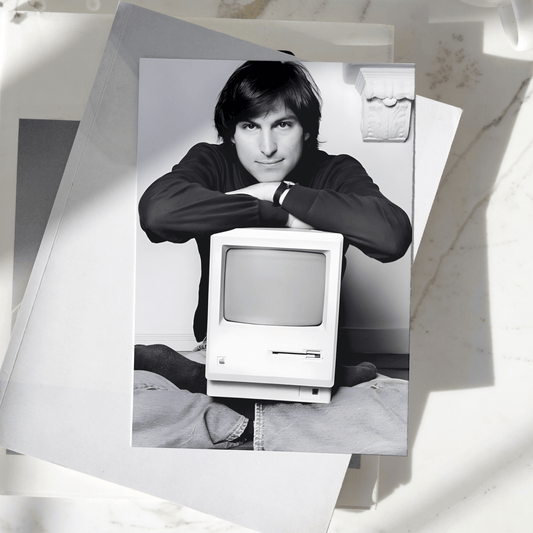 Steve Jobs poster featuring the Apple co-founder with a vintage Macintosh computer displayed on a desk, premium technology wall art print.