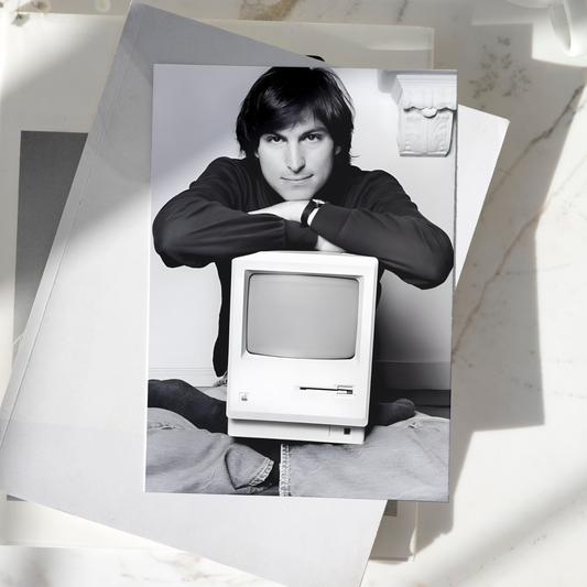 Steve Jobs poster featuring the Apple co-founder with a vintage Macintosh computer displayed on a desk, premium technology wall art print.