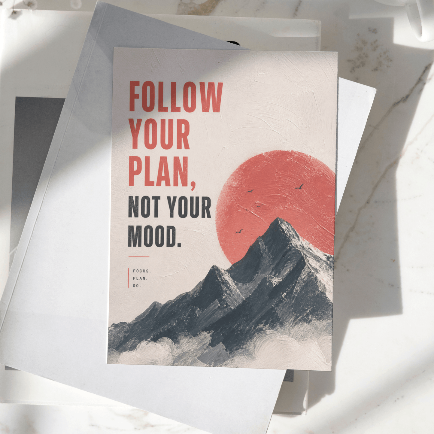 Follow Your Plan Not Your Mood motivational poster displayed on a desk, featuring mountain landscape artwork and a red sun design, premium inspirational wall art print