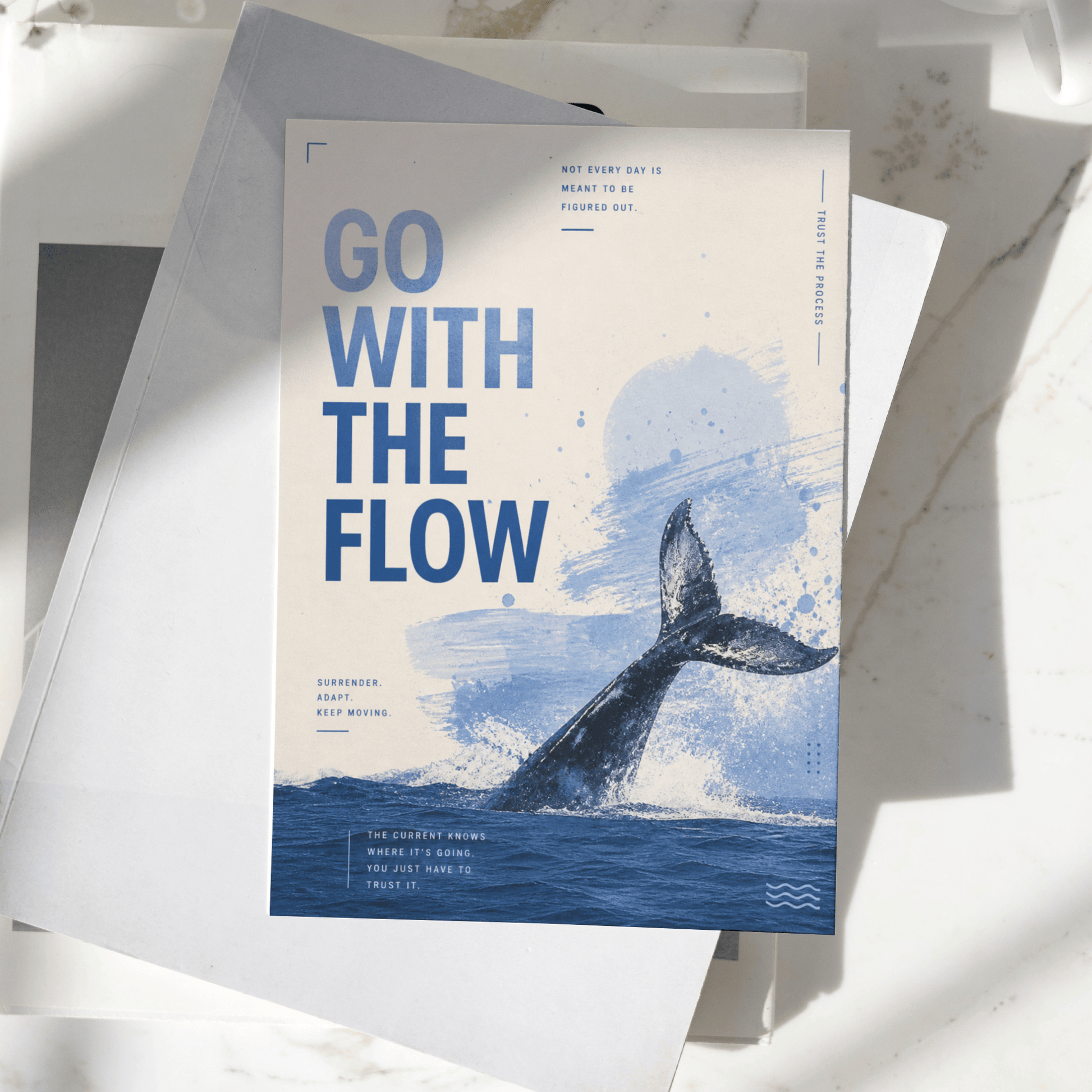 Go With The Flow motivational poster displayed on a desk, featuring a whale tail emerging from the ocean and calming blue artwork, premium inspirational wall art print.